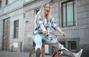 Smiling woman riding a vintage bicycle in a lively city street.